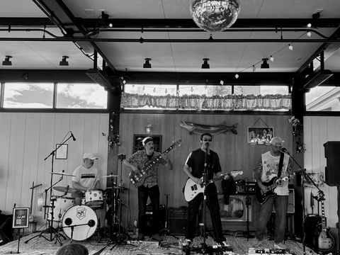 The Night Shift playing live under a disco ball: drums, bass, lead vocal and guitar, and guitar